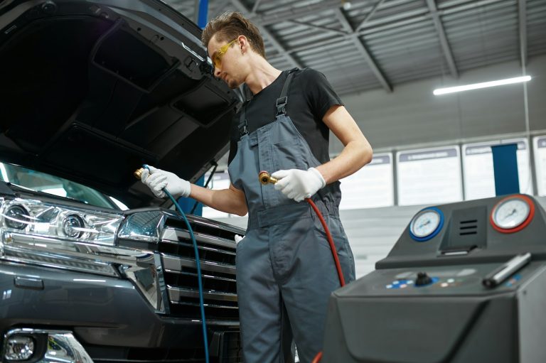 Male mechanic refills air conditioner, car service